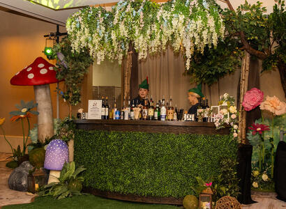 Custom-built topiary bar with oversized mushrooms and a hanging flower lantern