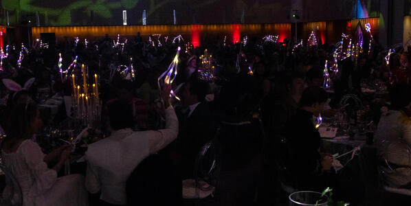 Guests holding light-up wands that were used in place of bidding paddles
